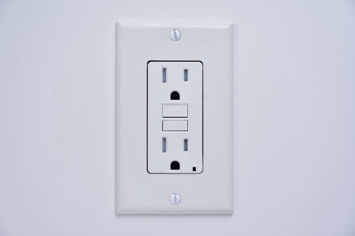 A picture of an standard American power outlet. It is white in color.